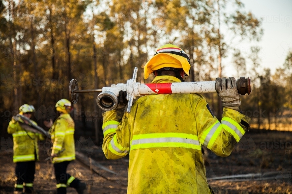 Fire and rescue man in fire brigade at grass fire emergency site with water hydrant - Australian Stock Image