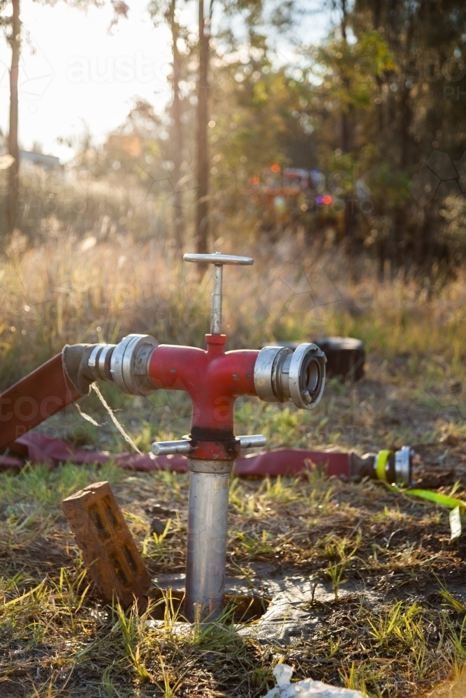 Fire Hydrant for fighting rural fires with hose attached and sun flare - Australian Stock Image