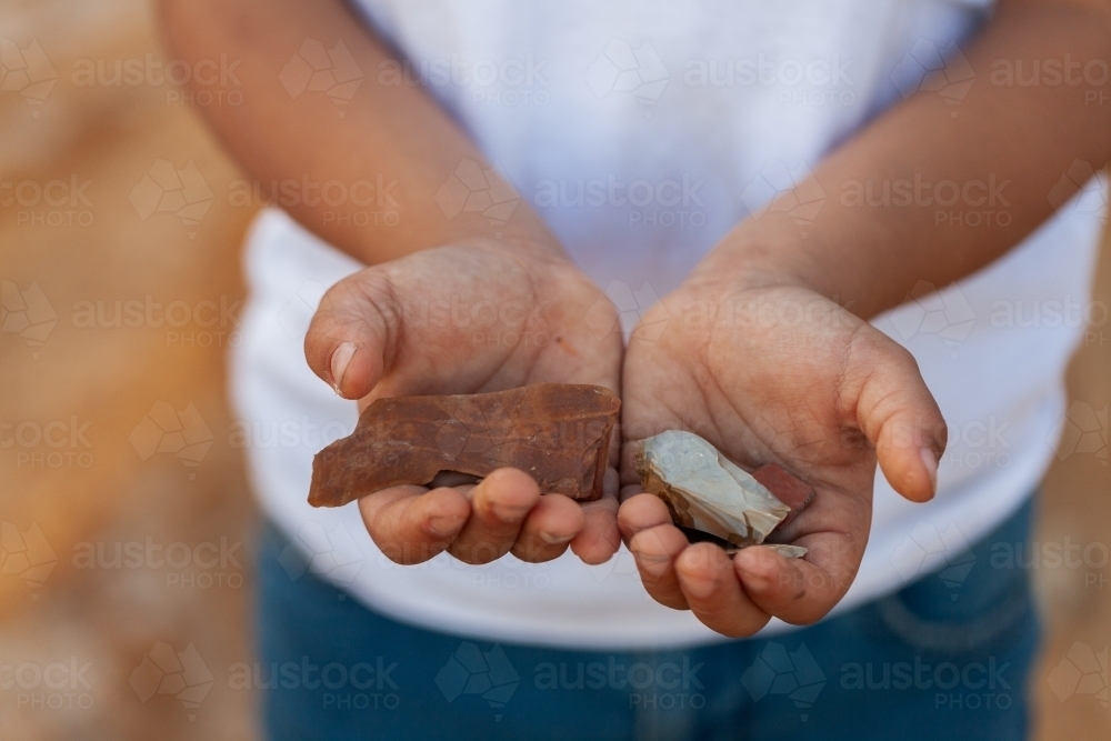 First Nation Australian child holding aboriginal artefact stones in hands - Australian Stock Image