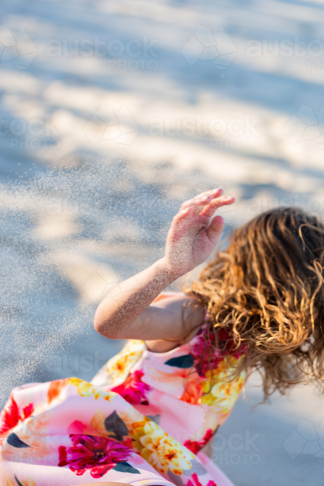 First Nations Australian Torres Strait Islander kid rolling down sand dune at the beach - Australian Stock Image