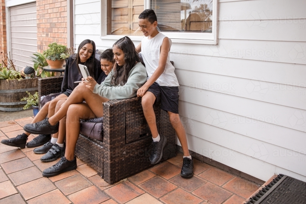 First nations family sitting together on couch outside - Australian Stock Image