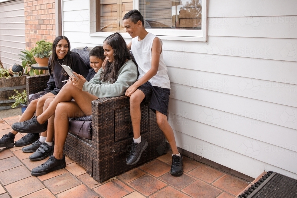 First nations family sitting together on couch outside - Australian Stock Image