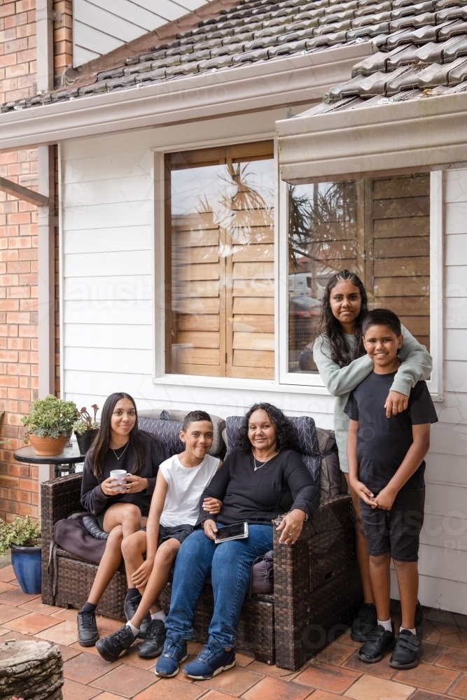 First nations family sitting together on couch outside - Australian Stock Image