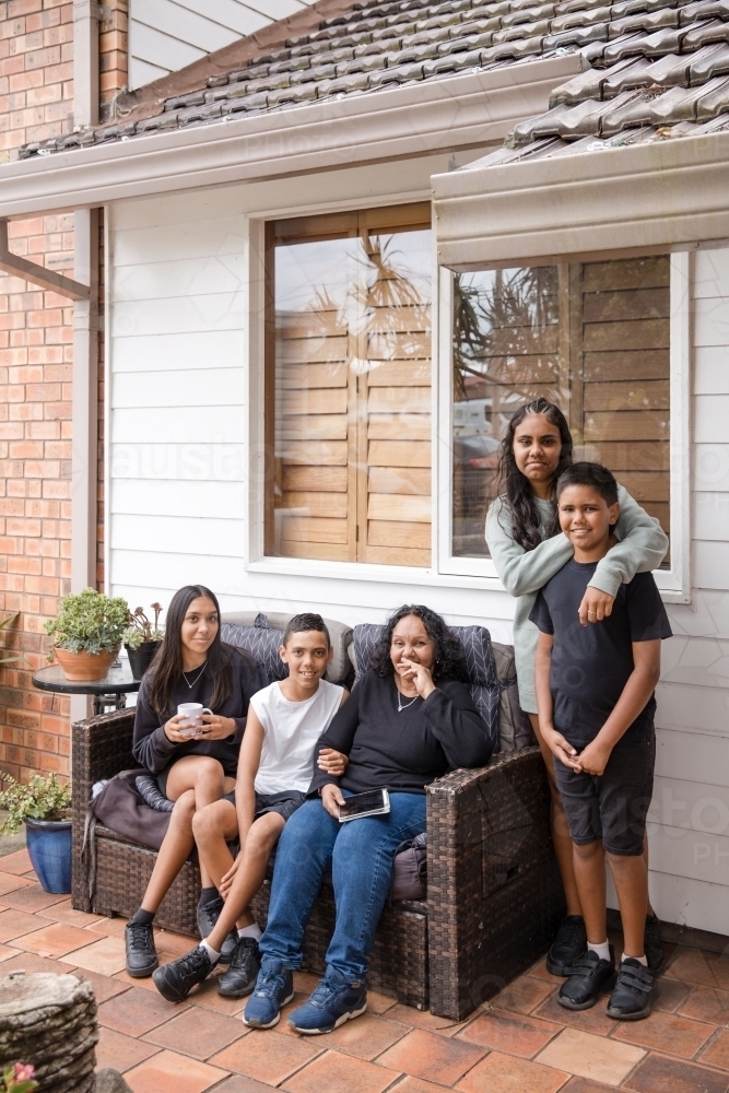 First nations family sitting together on couch outside - Australian Stock Image