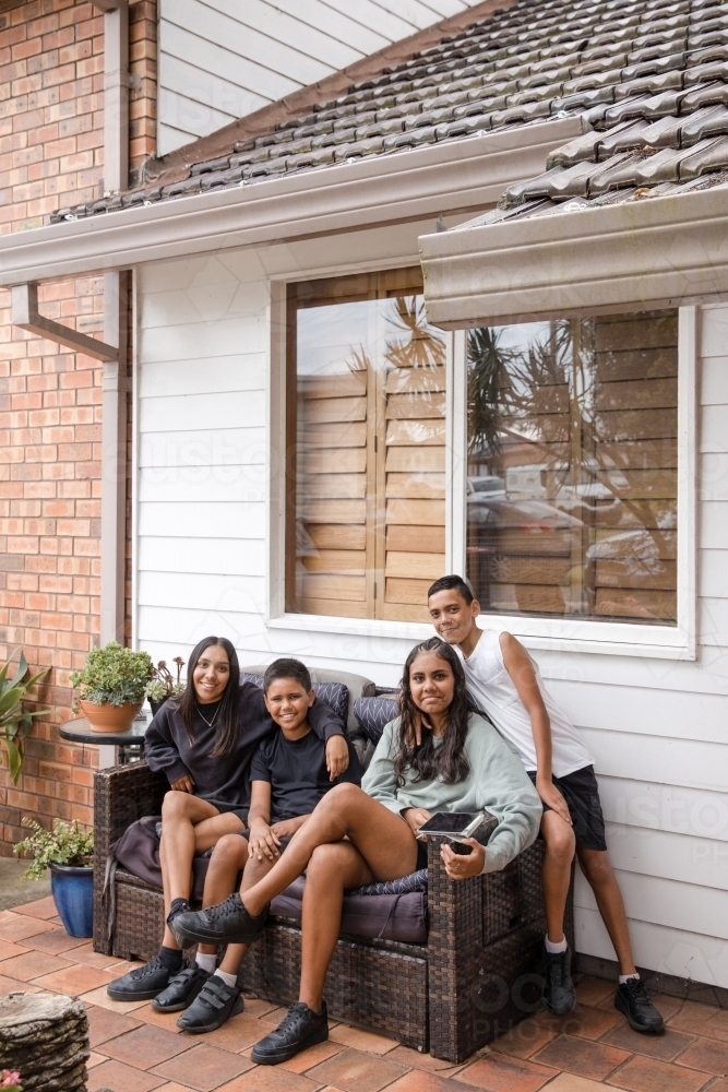 First nations family sitting together on couch outside - Australian Stock Image