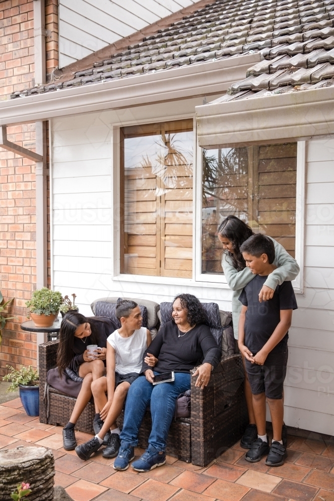 First nations family sitting together on couch outside - Australian Stock Image