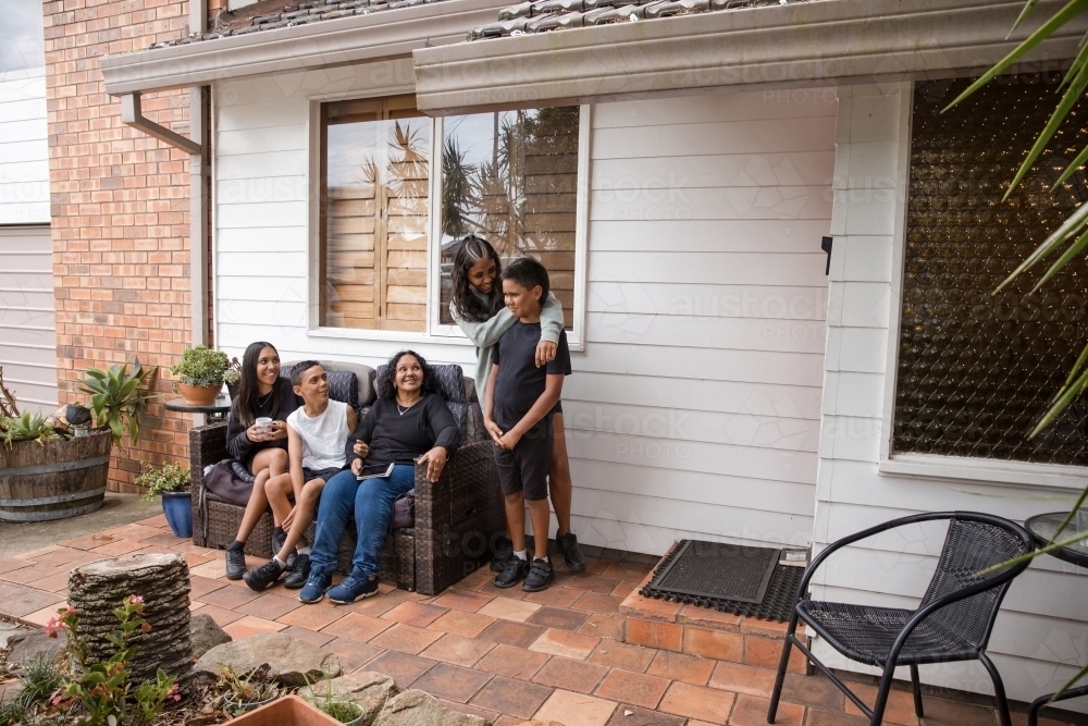 First nations family sitting together on couch outside - Australian Stock Image