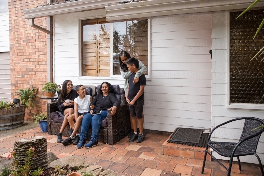 First nations family sitting together on couch outside - Australian Stock Image