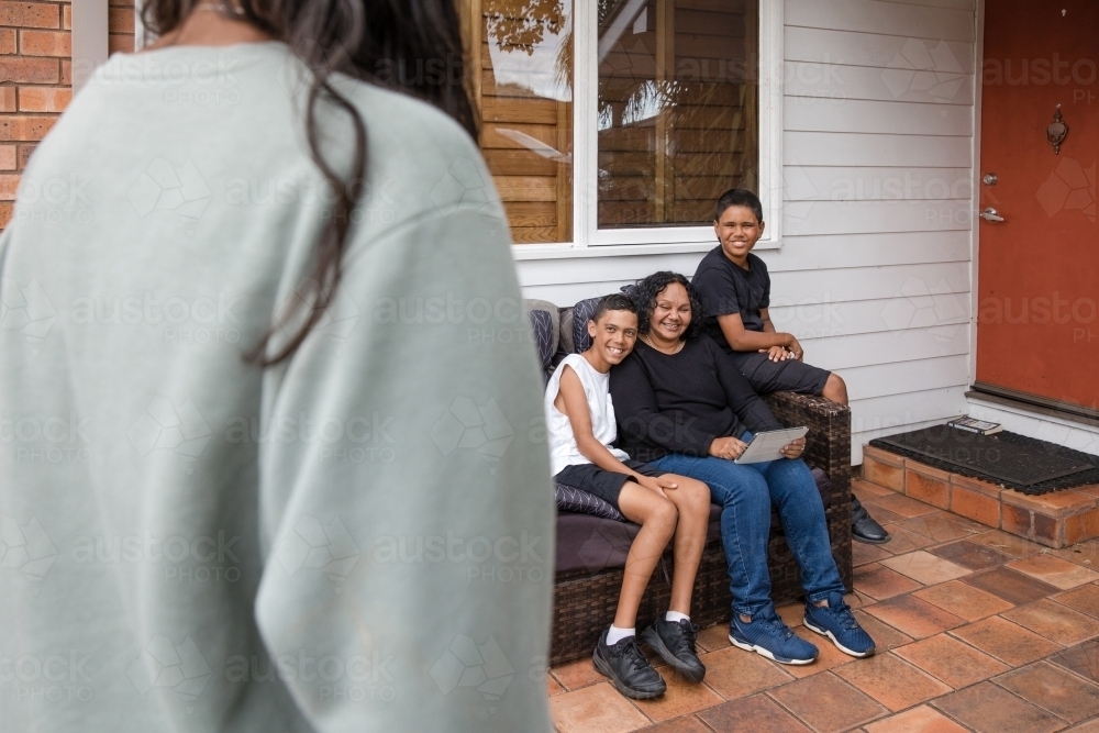 First nations family sitting together on couch outside - Australian Stock Image