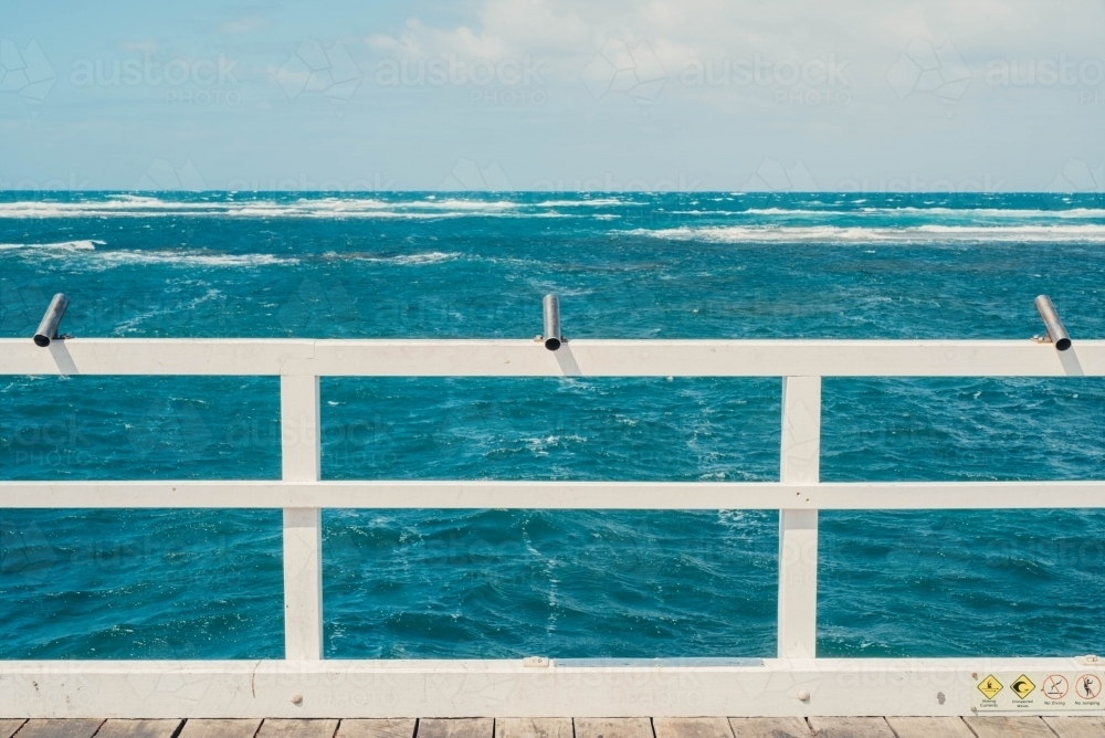 Fishing poles on a pier by the ocean - Australian Stock Image