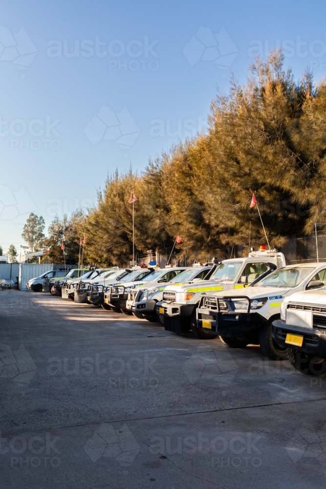 Fleet of white utility vehicles lined up outside mechanics repair shed - Australian Stock Image