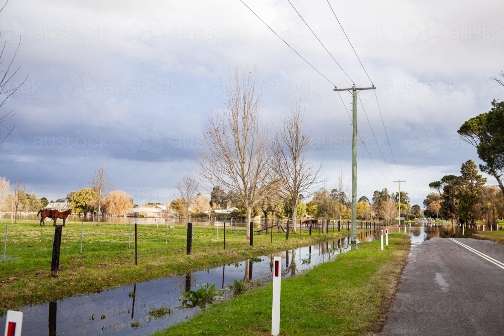 Flood water in paddock beside road at edge of town - Australian Stock Image