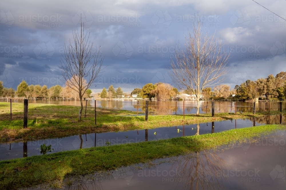 Flood water in paddock beside road at edge of town - Australian Stock Image