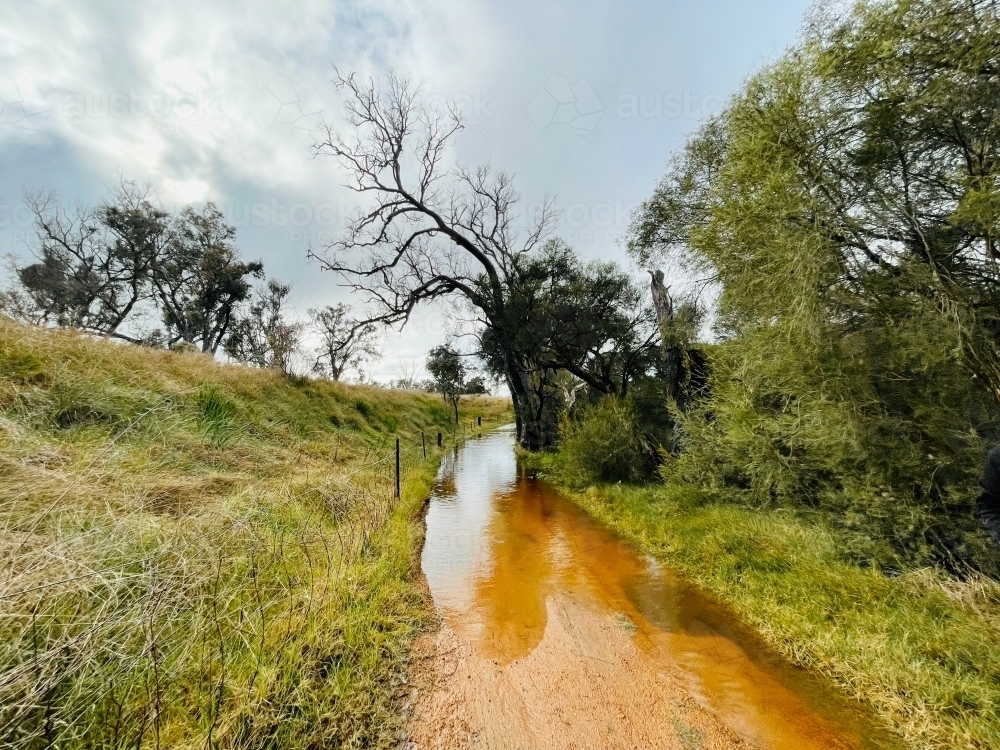 Flooding on sandy trail in farm and bushland - Australian Stock Image