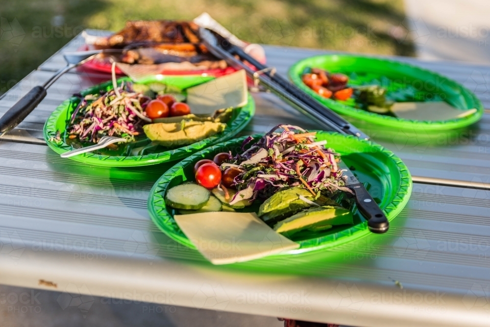 Food on plates on silver park table outdoors - Australian Stock Image