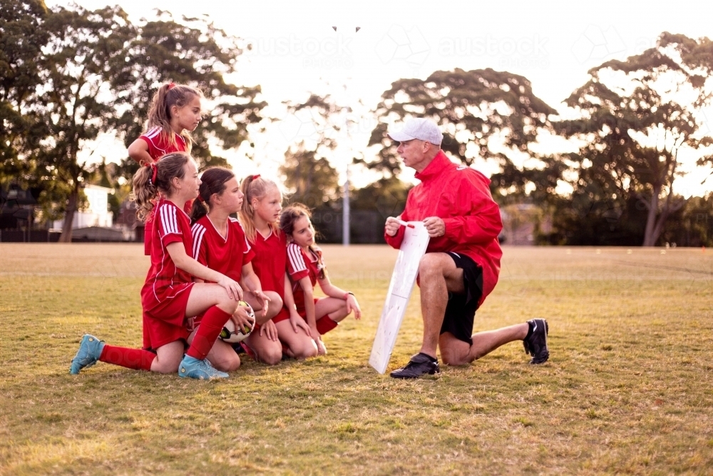 Football coach explaining strategy to his team of tween girls - Australian Stock Image