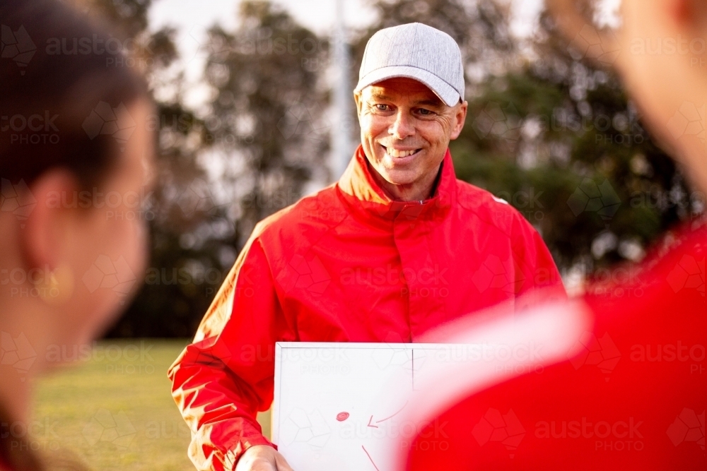 Football coach explaining strategy to his team of tween girls - Australian Stock Image