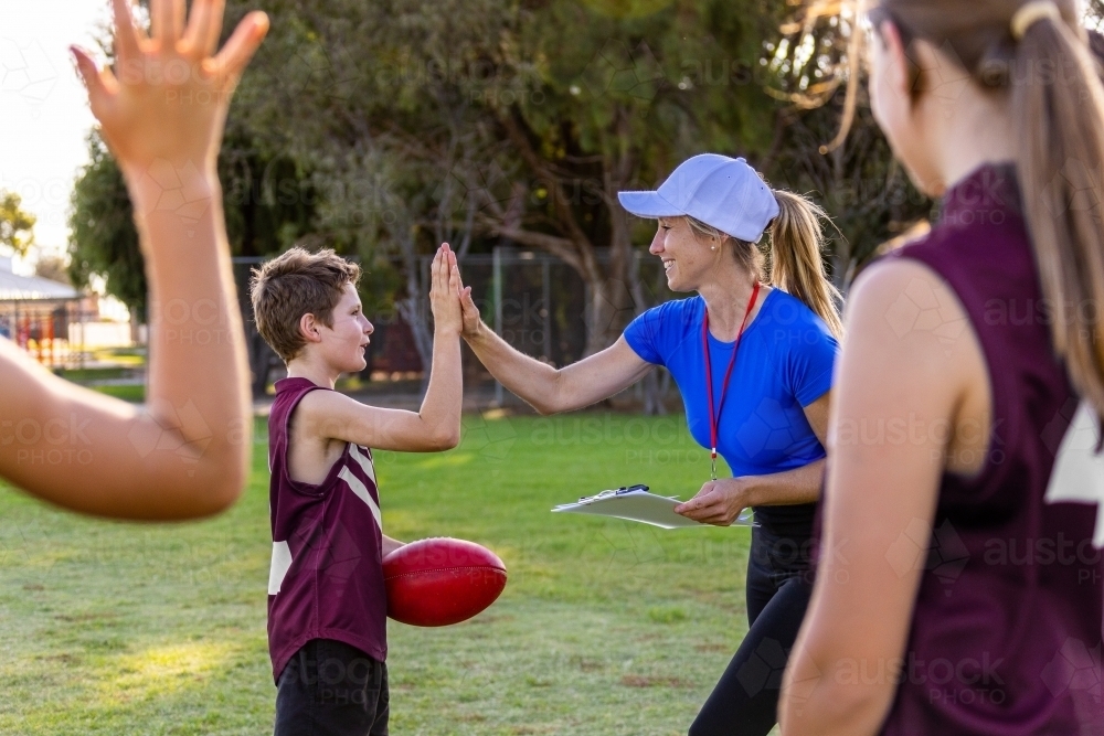 football coach giving high five to schoolboy at training - Australian Stock Image