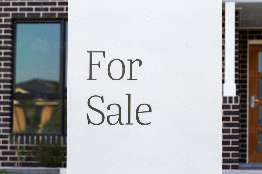 For sale sign outside of new brick house on real estate market - Australian Stock Image