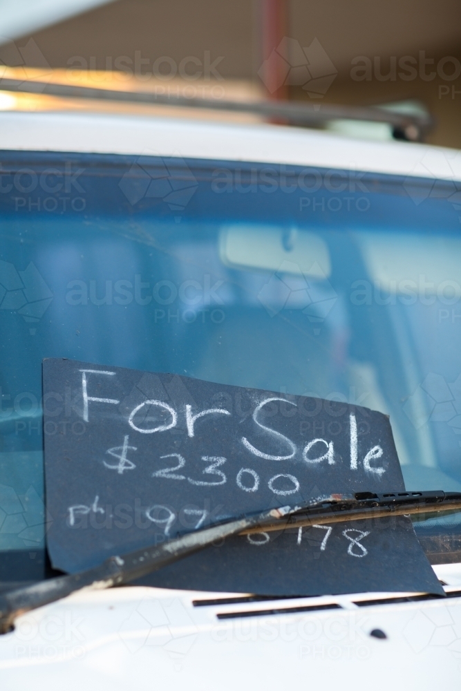 For Sale sign stuck under a windscreen wiper of a cheap car - Australian Stock Image