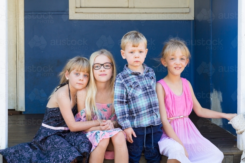 Four little kids sitting on step - Australian Stock Image