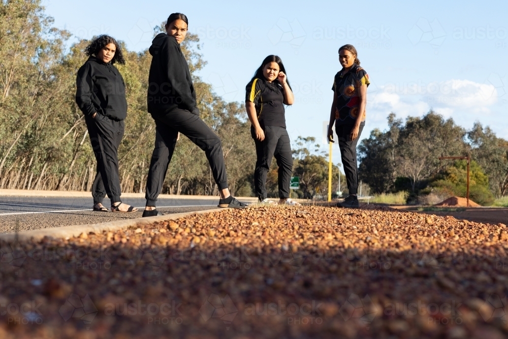 four teenagers dressed in black standing on the edge of a road - Australian Stock Image