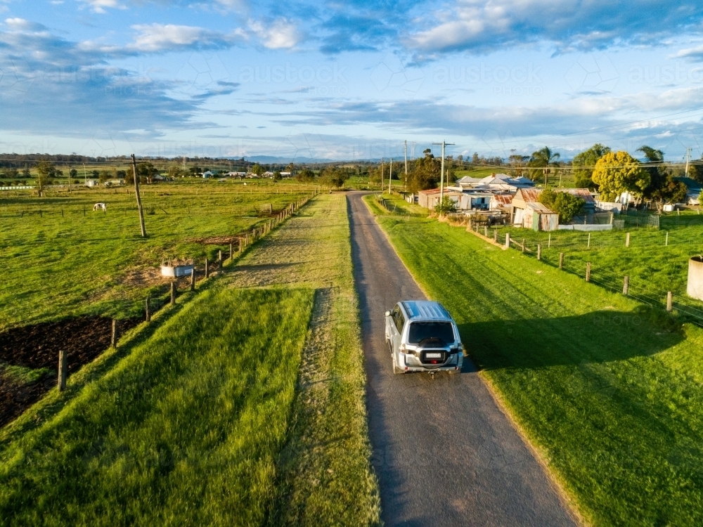 Four wheel drive car travelling through farmland on narrow country road trip adventure - Australian Stock Image