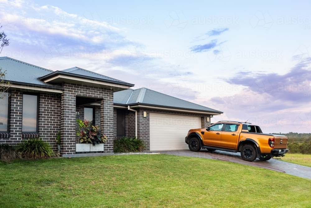 four wheel drive ute parked on driveway of home at dusk - Australian Stock Image