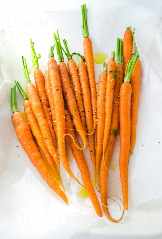 Fresh spring baby carrots drizzled with olive oil ready to roast - Australian Stock Image