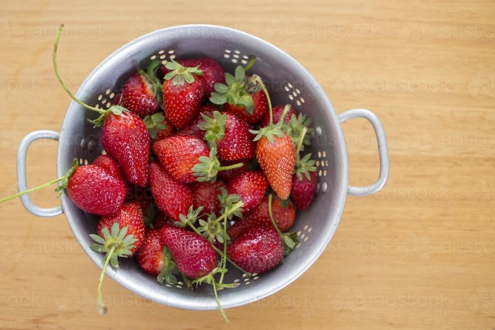 Fresh strawberries in steel colander - Australian Stock Image