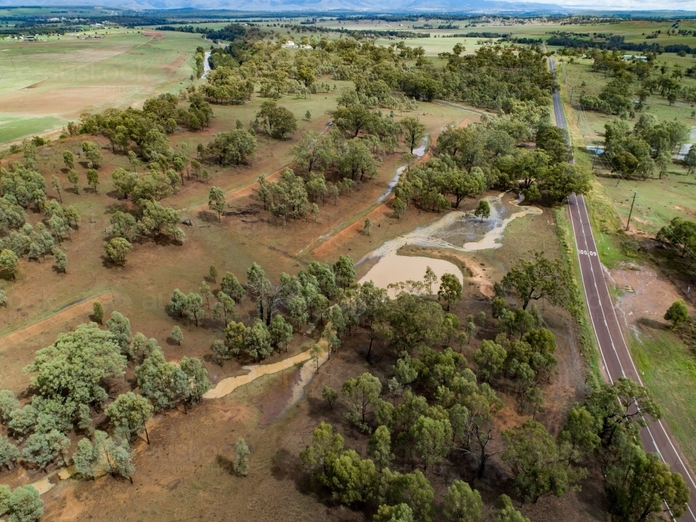 Full creek and overflowing dam in rural paddock - Australian Stock Image