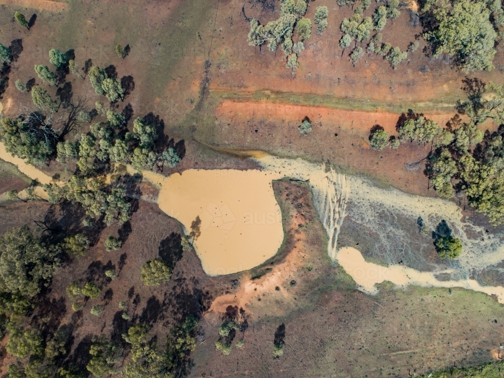 Full creek and overflowing dam in rural paddock - Australian Stock Image