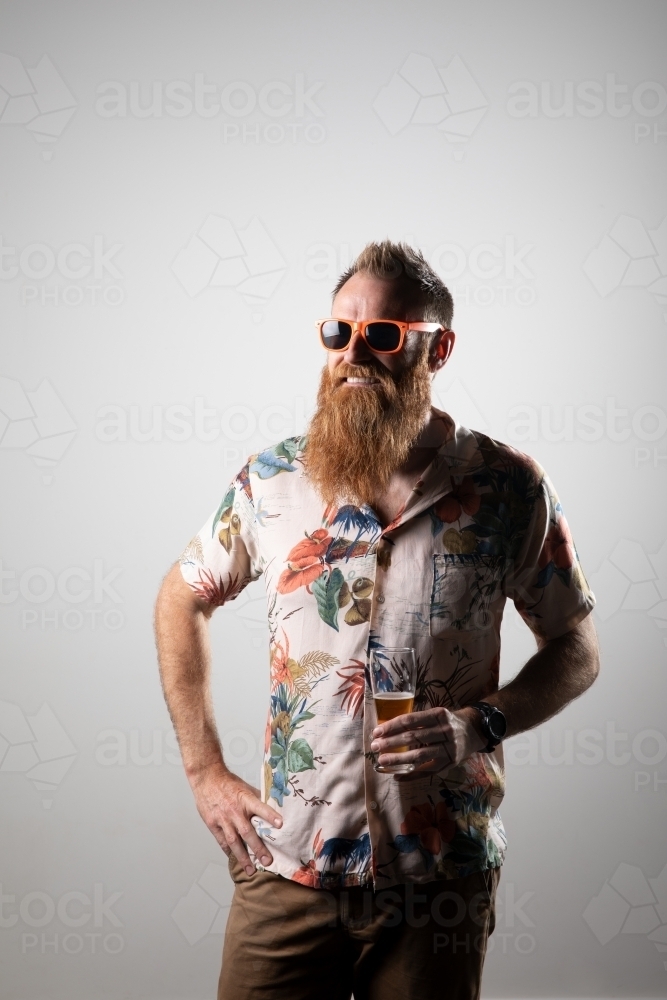 Funky man posing for photographs, holding a glass of beer - Australian Stock Image