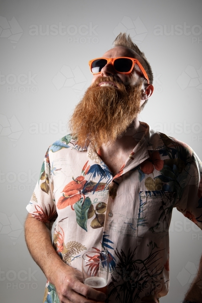 Funky man posing for photographs, holding a glass of beer - Australian Stock Image