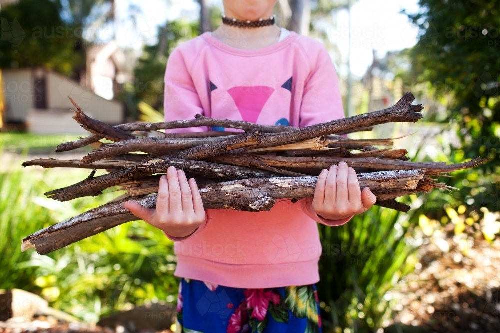 Girl carrying some sticks for firewood - Australian Stock Image