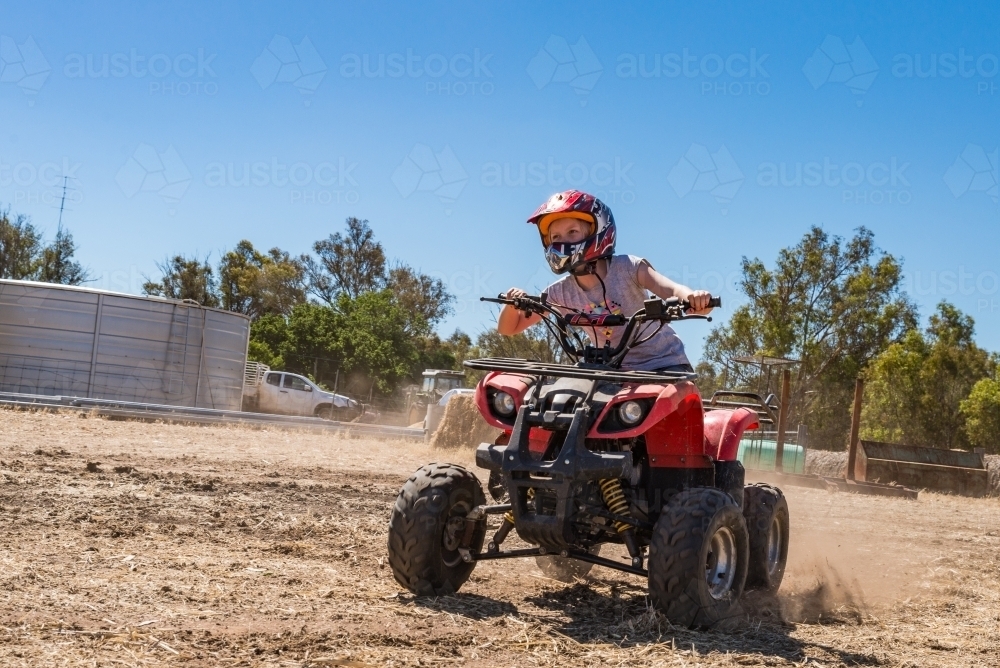 Girl Child Riding a 4 Wheeled Motorbike on Farm - Australian Stock Image