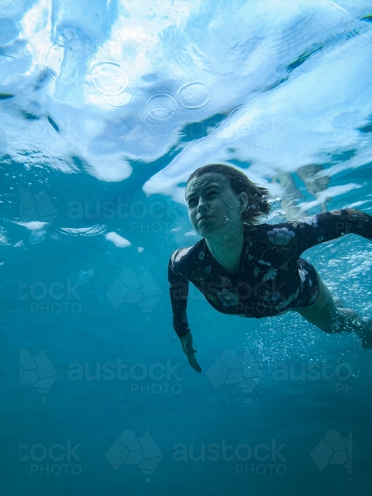 Girl diving underwater holding breath in full swimsuit - Australian Stock Image