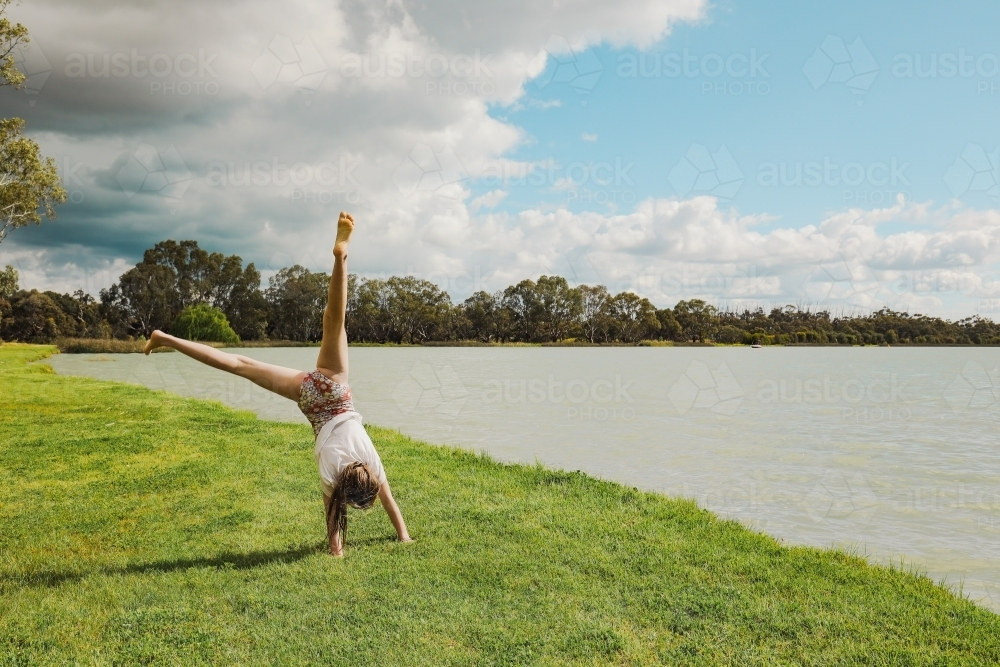 Girl doing cartwheel next to Lake in Boort, Victoria - Australian Stock Image