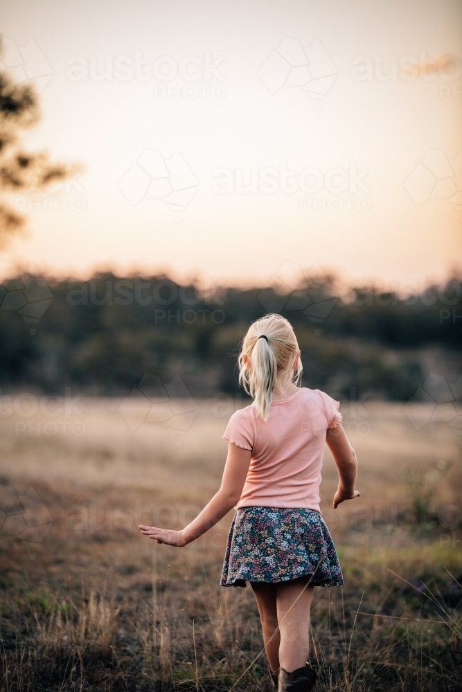 Girl facing into the landscape as she walks away - Australian Stock Image