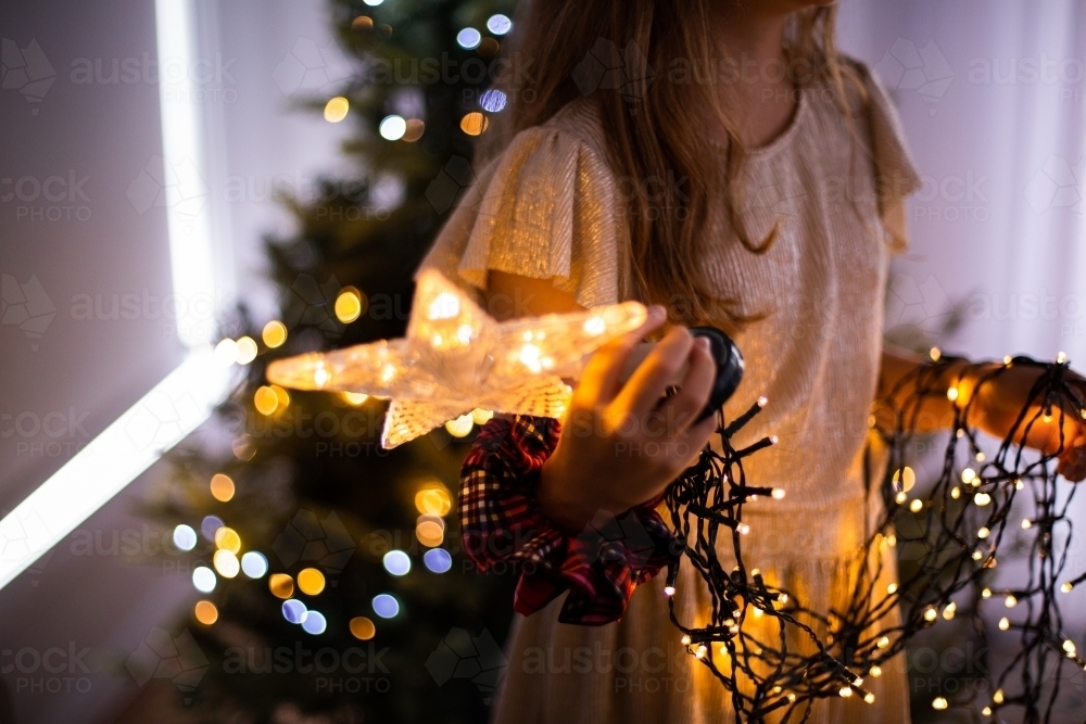 girl holding a light up christmas tree topper - Australian Stock Image