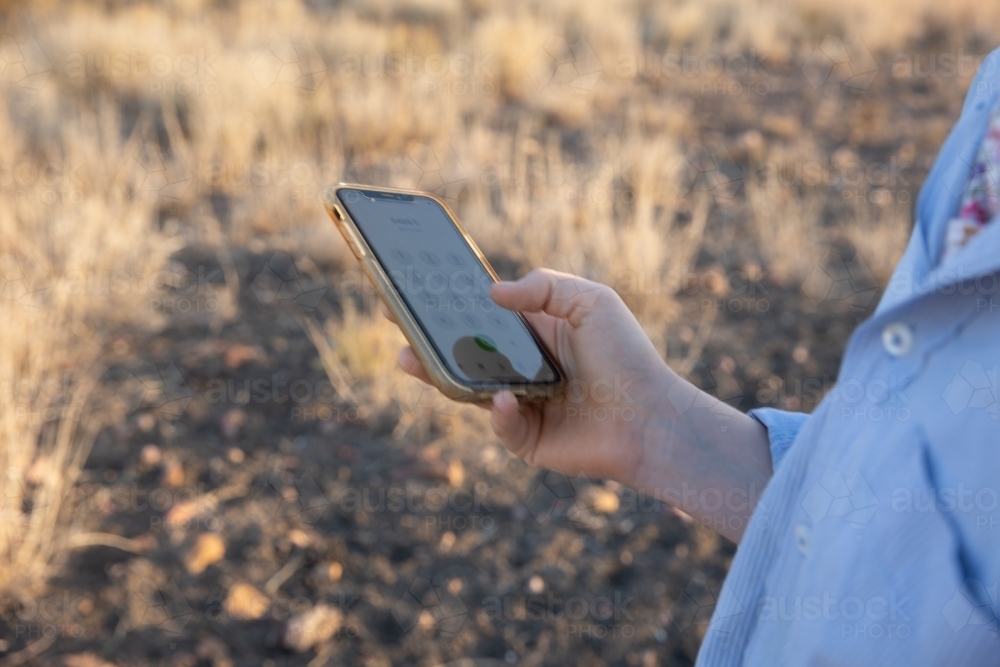 Girl holding mobile phone in paddock - Australian Stock Image