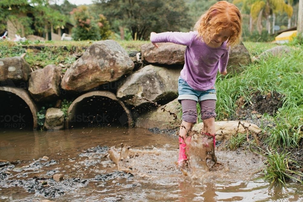 Girl jumping in a puddle - Australian Stock Image