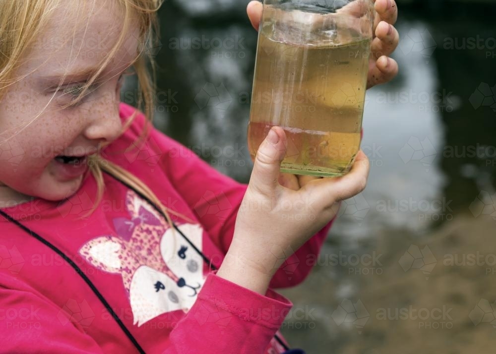 Girl Looking in Jar at Fish - Australian Stock Image