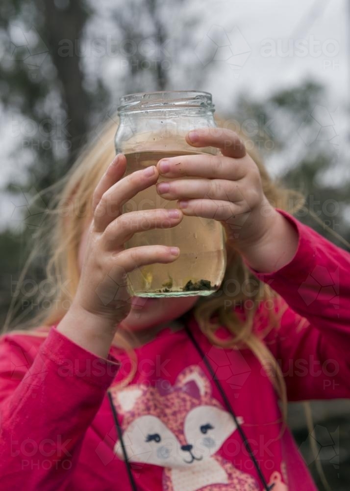 Girl Looking into Glass Jar - Australian Stock Image