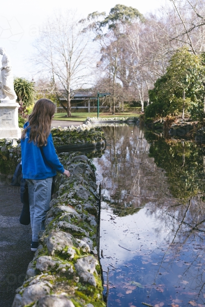 Girl looking into water reflections at Ballarat Botanic Garden - Australian Stock Image