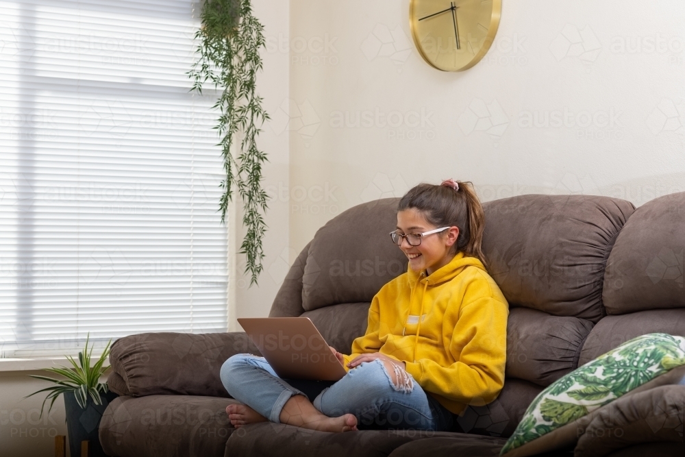 Girl on sofa with laptop computer - Australian Stock Image