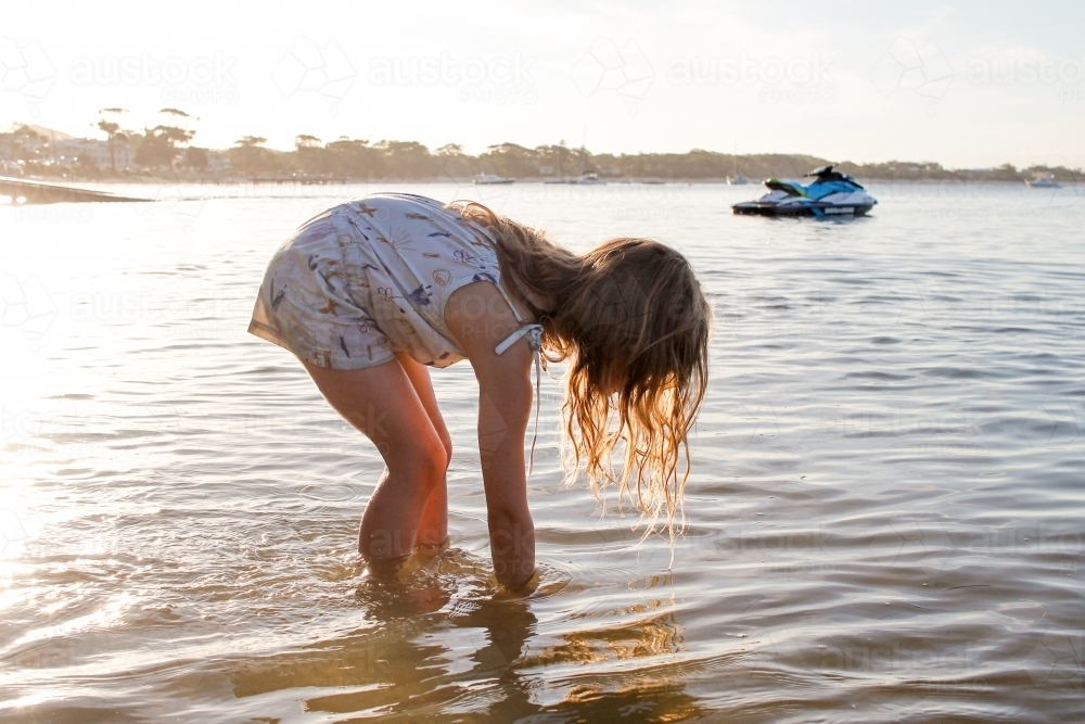 Girl picking up something on the beach - Australian Stock Image