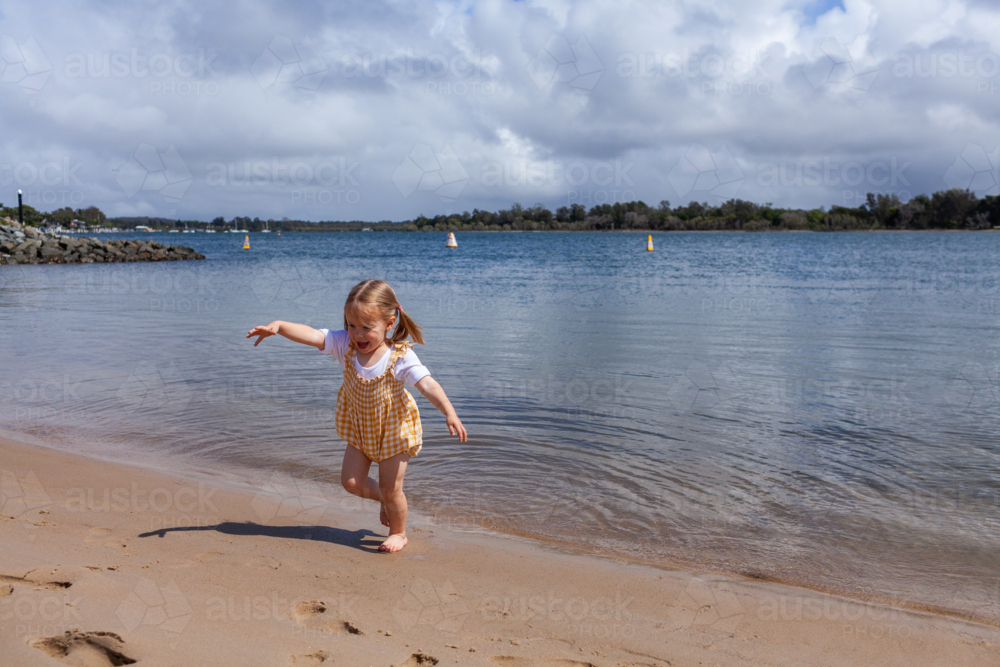 girl playing by water on tiny beach on the shore of coastal Hastings river in Port Macquarie - Australian Stock Image