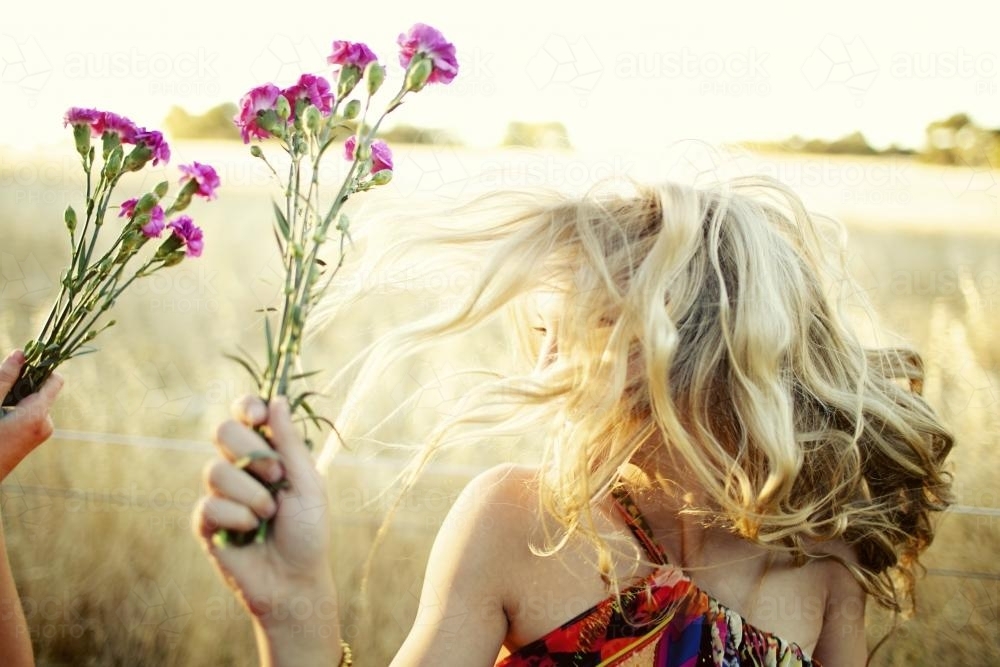 Girl playing with flowers in a field - Australian Stock Image