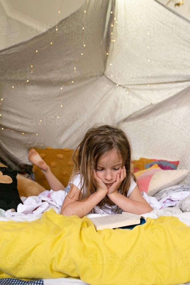 Girl reading a book in the tent - Australian Stock Image